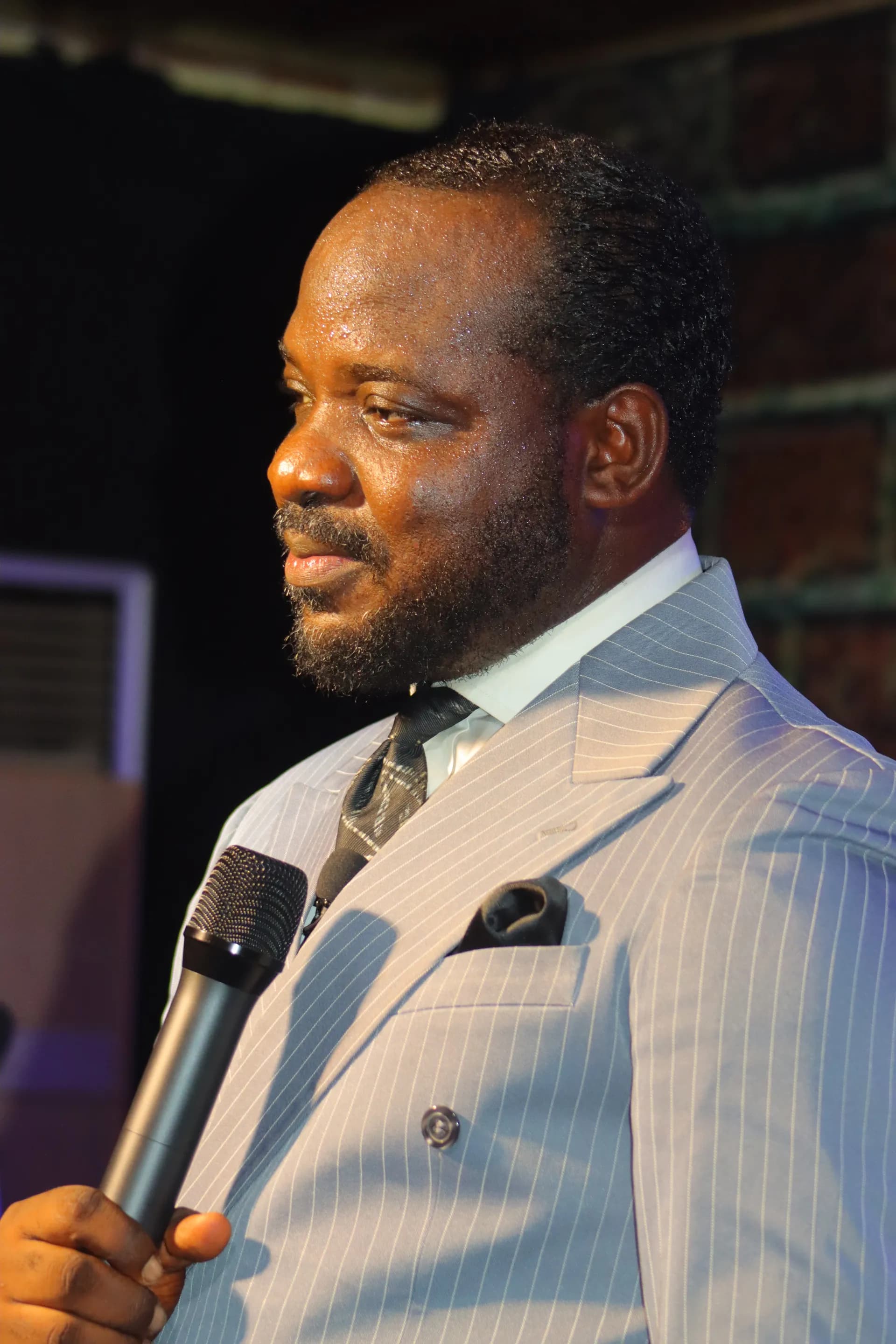 Pastor Aringa mid-message, microphone in hand