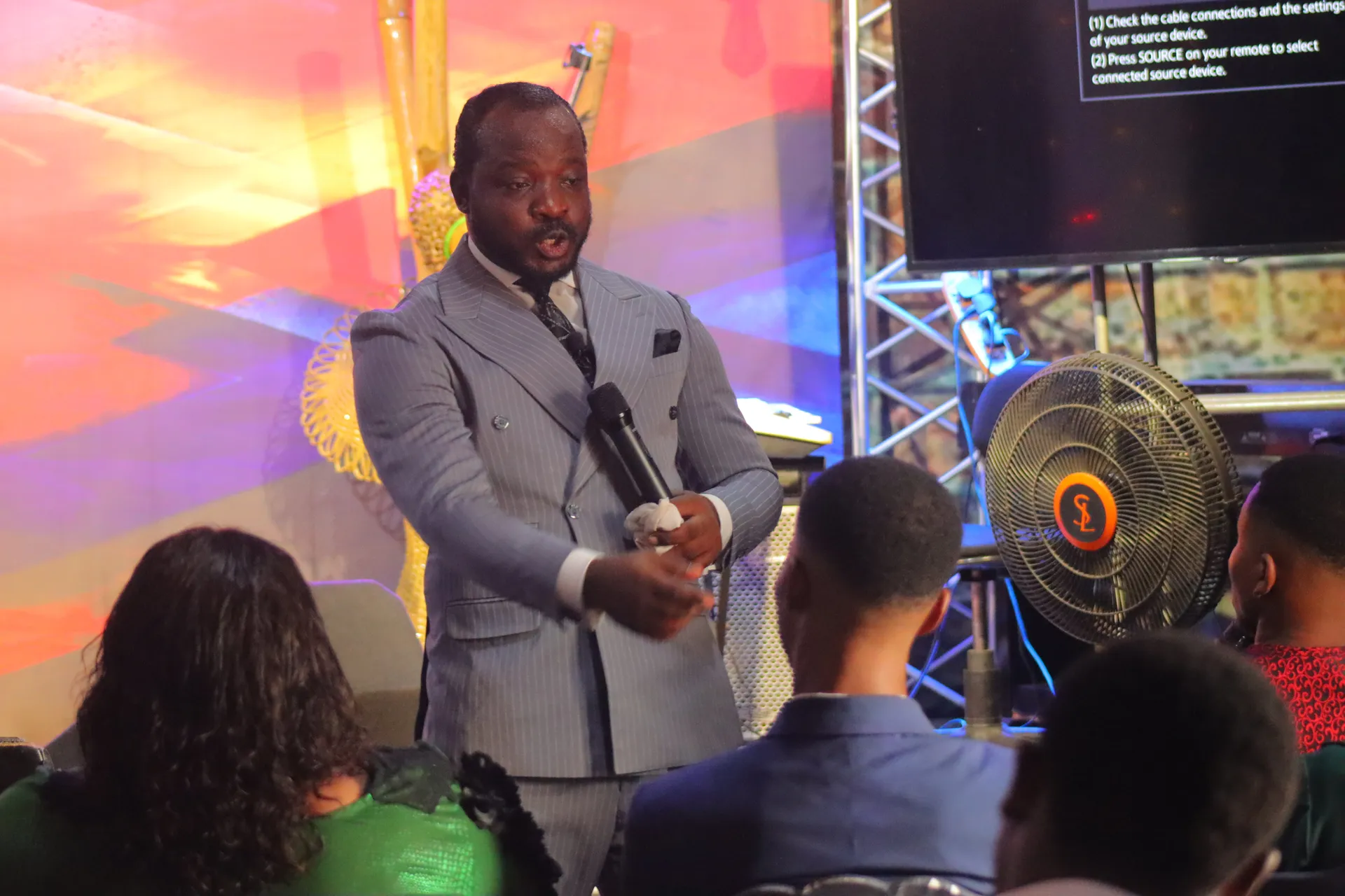 Pastor Aringa teaching among the congregation, microphone in hand