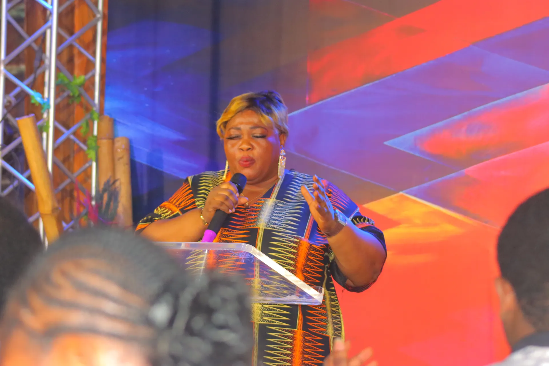 A minister preaching at the podium, hand lifted as she declares the Word