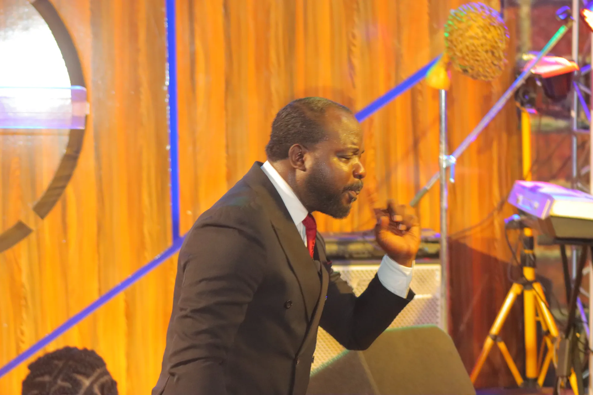 Pastor preaching before a golden-lit backdrop at Worldlight International Church
